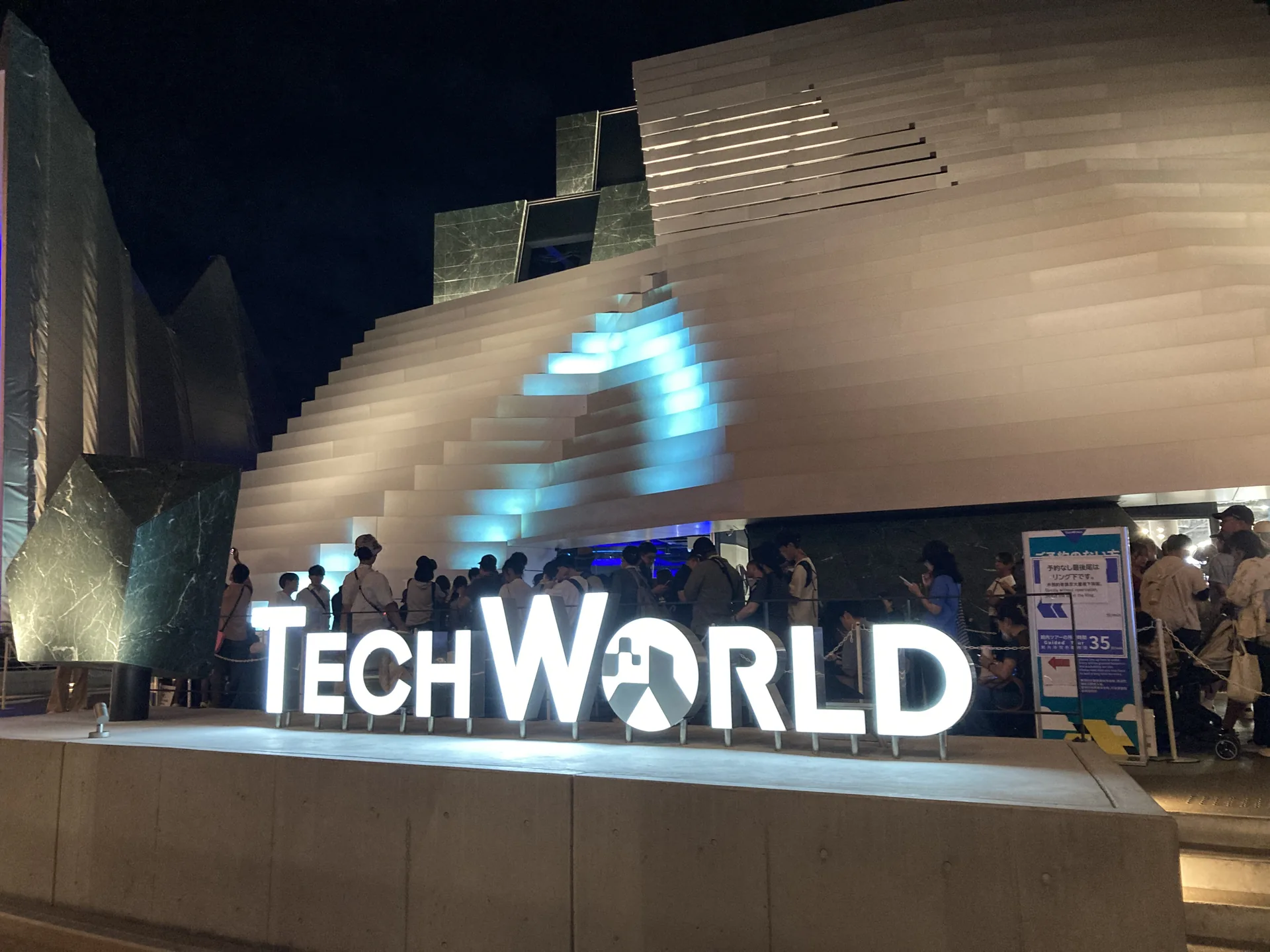 夜の万博、TechWorldパビリオンの照明が浮かぶ会場の様子