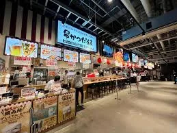 大阪のれんめぐり 〜食と祭EXPO〜。串かつだるまの店舗看板と、店頭でたこ焼きを焼くスタッフ
