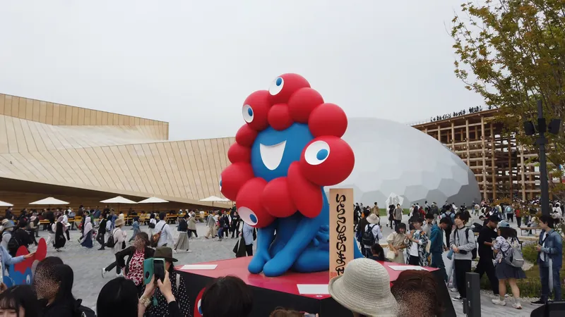 大屋根リングを背に、どっしりと座るミャクミャク像（2025年・会場で現地撮影）