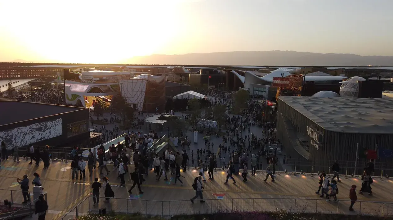 夕暮れの大阪・関西万博会場を俯瞰した全景。中央に大屋根リングと多数の来場者